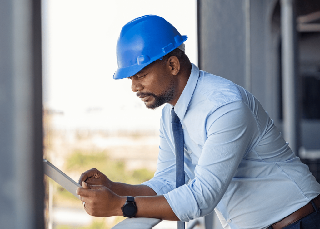 Male worker in hardhat using tablet computer