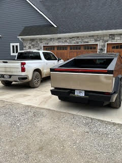 Tesla Cybertuck parked next to a Silverado.