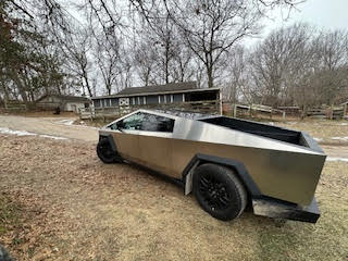 Tesla Cybertruck parked on a grassy hill.