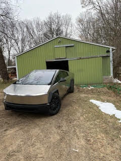 Tesla Cybertruck parked in front of a barn.