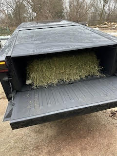 Tesla Cybertruck with a hay bale on the back.