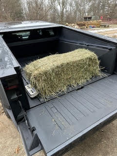 Tesla Cybertruck with a hay bale on the back.