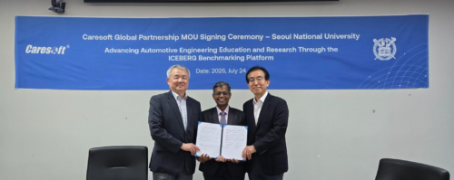 Three men in suits stand together, holding a signed document in front of a blue banner used for a signing ceremony.